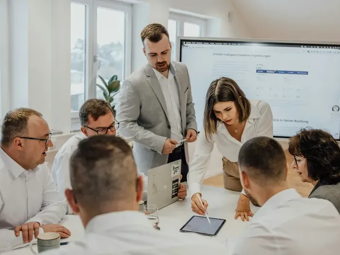 Group of professionals gathered around a table discussing ideas during a meeting with digital devices and charts